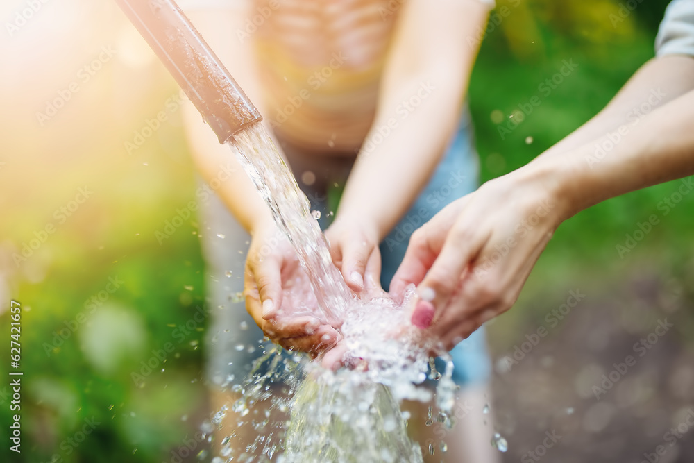 Close up view of womans and childs hands in natural source of water in the park.