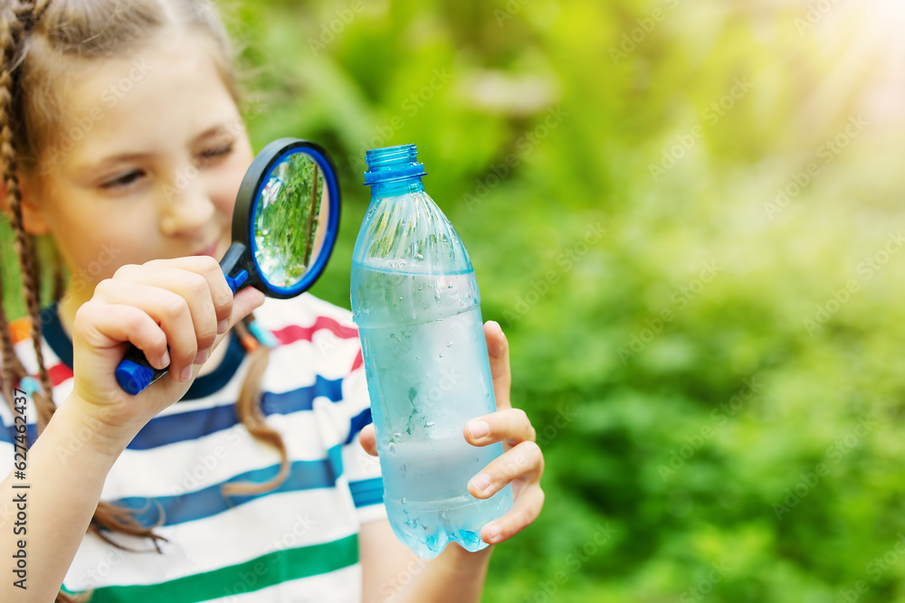 Girl studying water in a bottle with a magnifying glass.