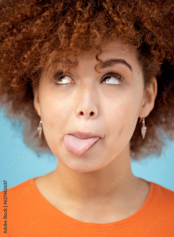 Comic, tongue and face with a black woman in studio on a blue background feeling funny or silly. Com