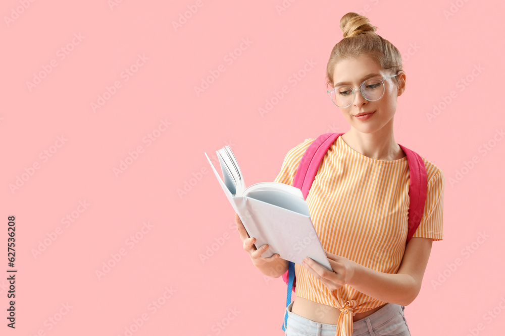 Female student reading book on pink background