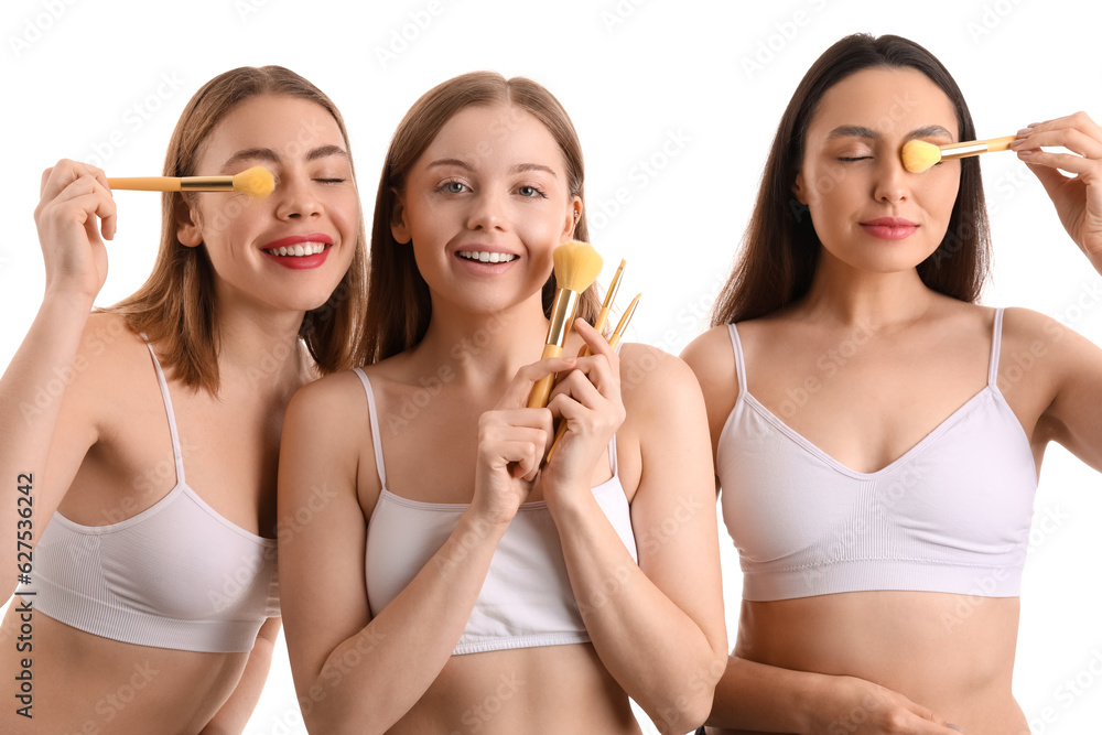 Young women with makeup brushes on white background