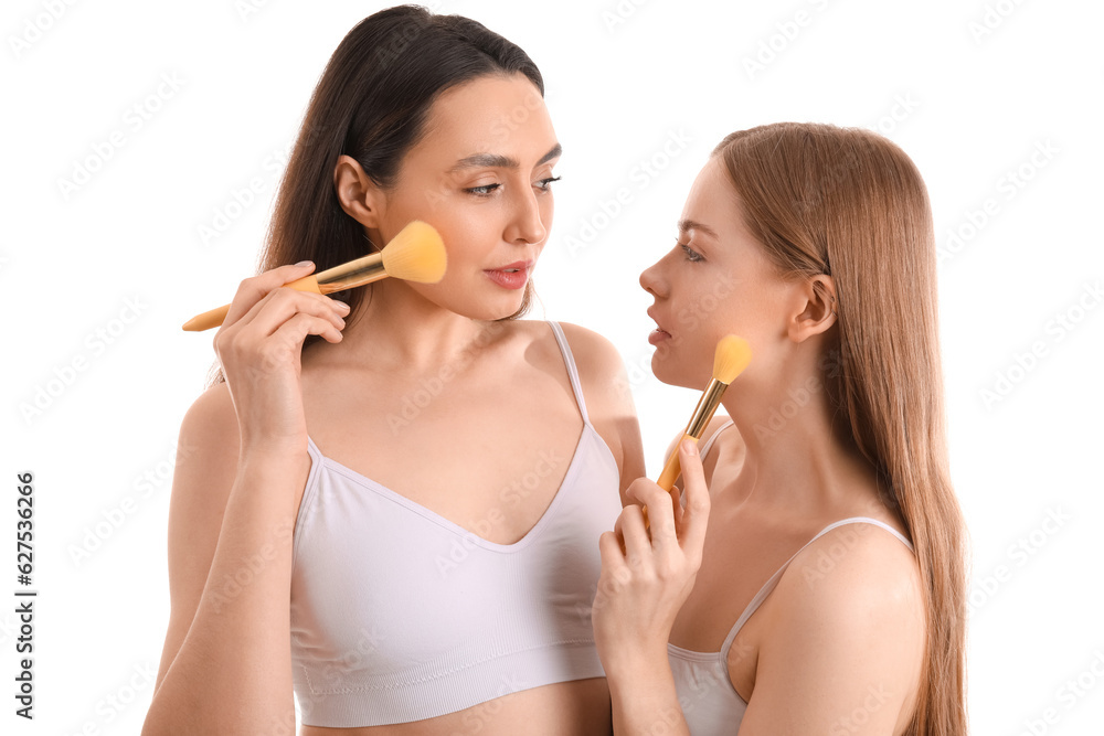 Young women with makeup brushes on white background