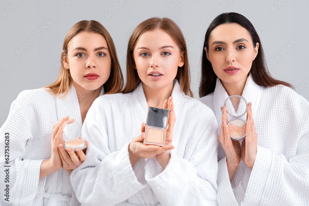 Young women with makeup powder on grey background