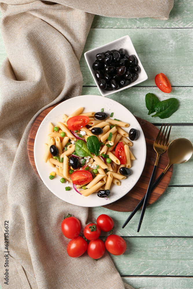 Plate with tasty pasta salad and ingredients on light wooden background