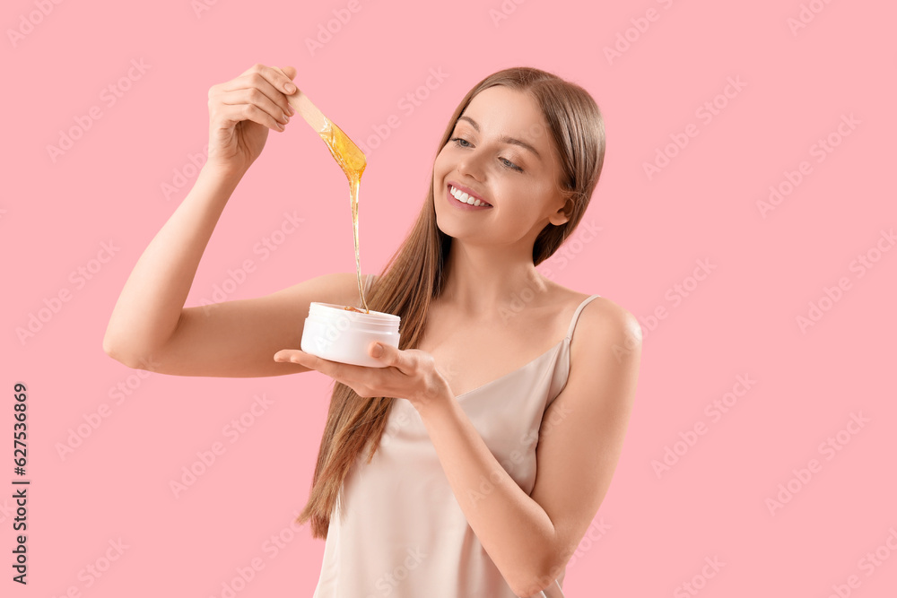 Pretty young woman with sugaring paste on pink background