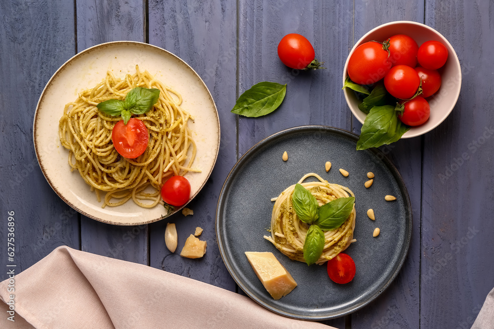 Plates with tasty pesto pasta and tomatoes on color wooden background