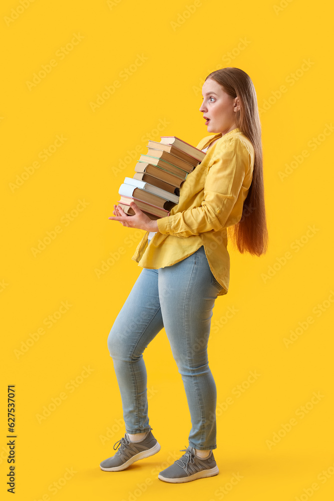 Young woman with stack of books on yellow background