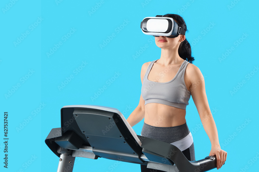 Beautiful woman in VR glasses training on treadmill against blue background