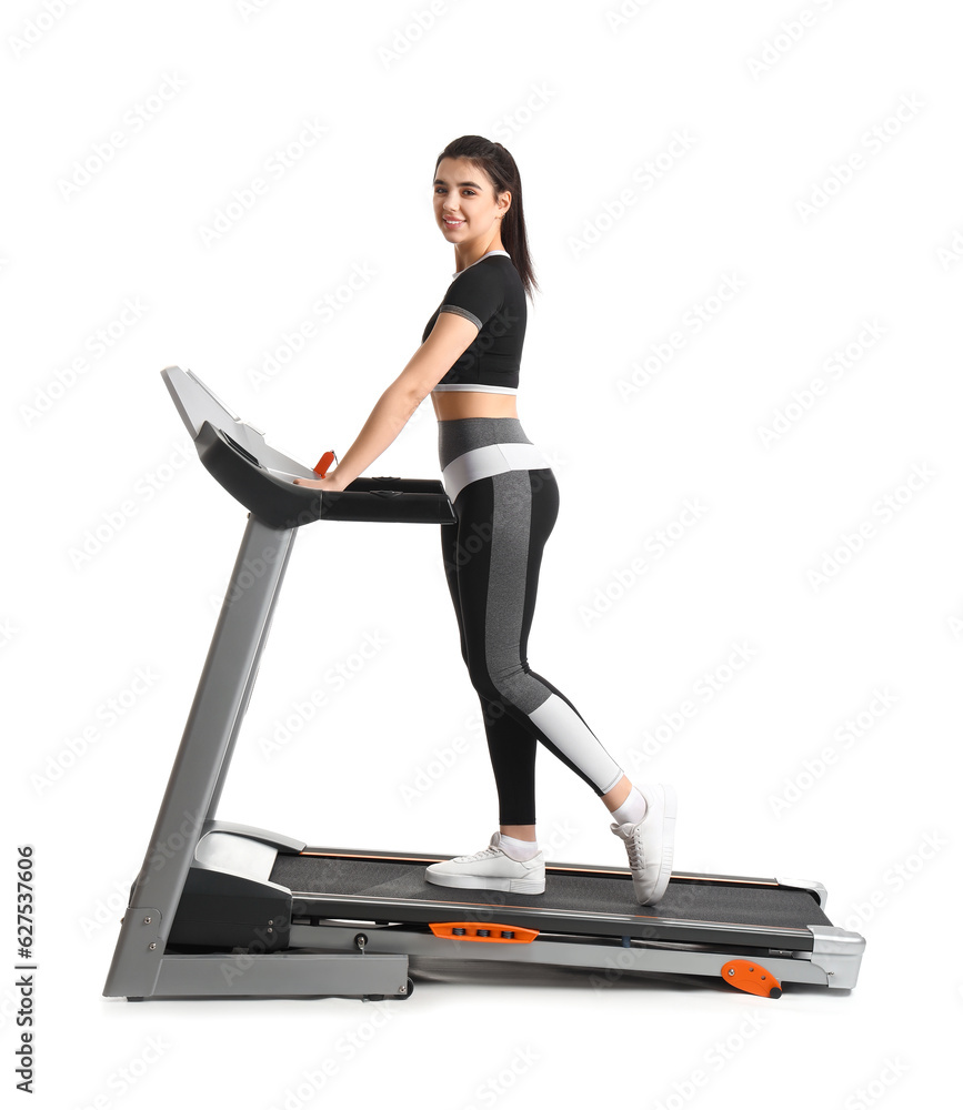 Sporty young woman training on treadmill against white background