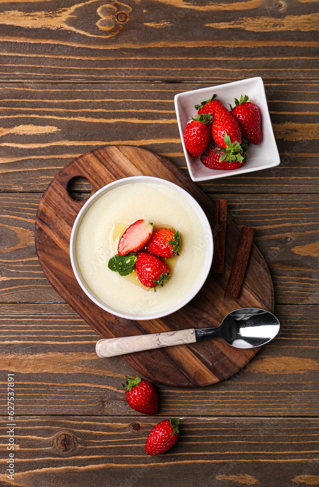 Bowl of tasty semolina porridge with strawberry on wooden background