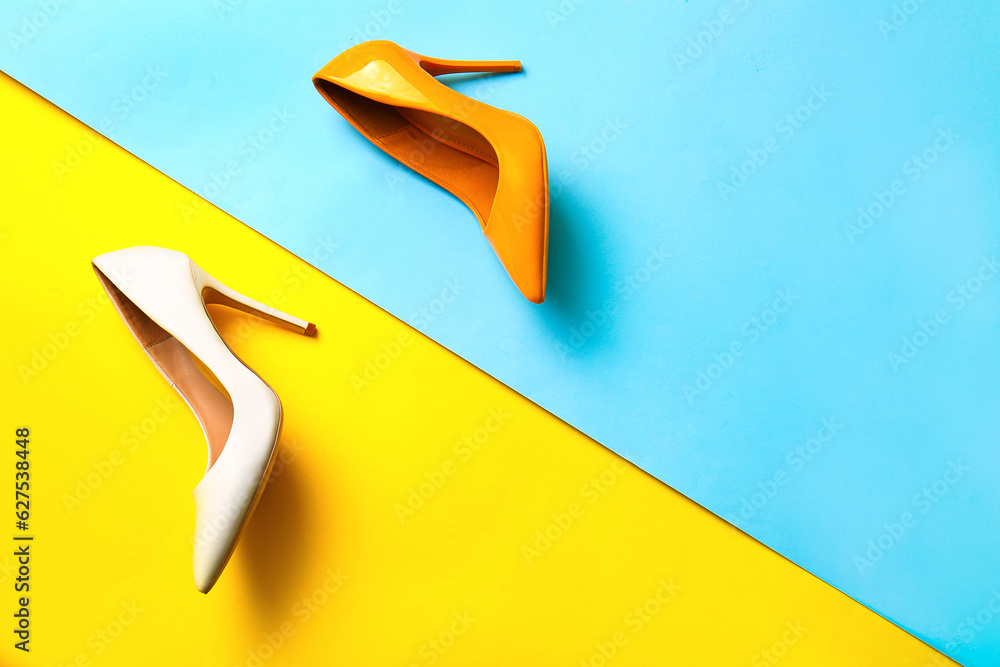 Fashionable high heeled shoes on color background