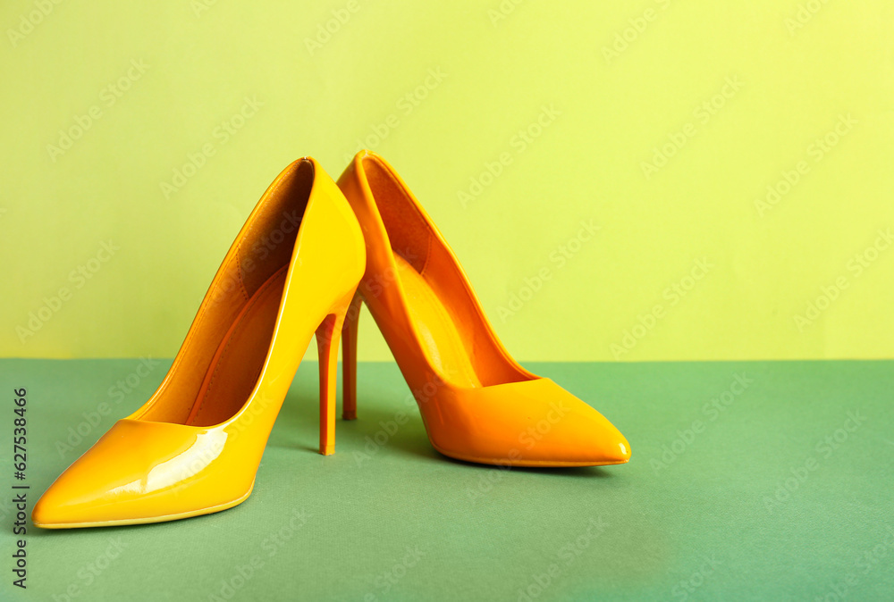 Pair of stylish high heeled shoes on green background