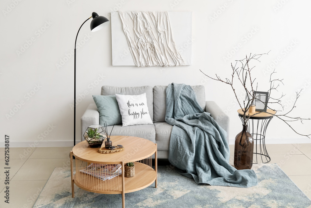 Interior of cozy living room with grey sofa and coffee table near white wall