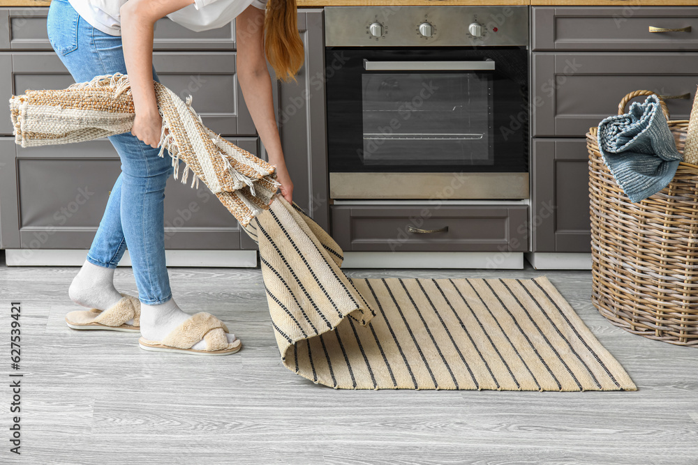 Woman placing rug on floor in modern kitchen