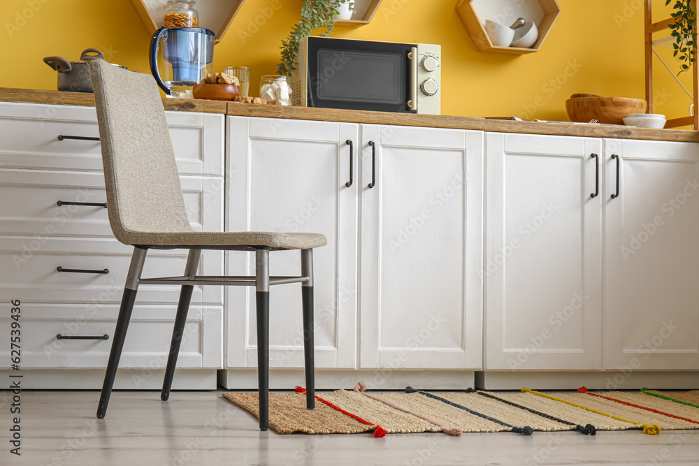 Chair and stylish rug on floor in modern kitchen