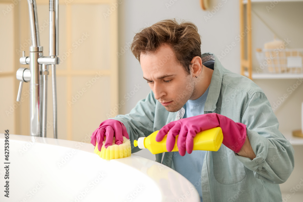 Young man cleaning bathtub at home