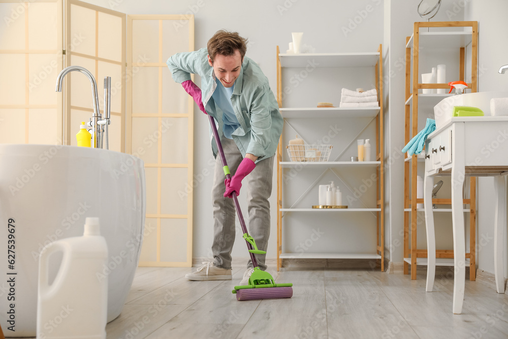 Young man mopping floor in bathroom