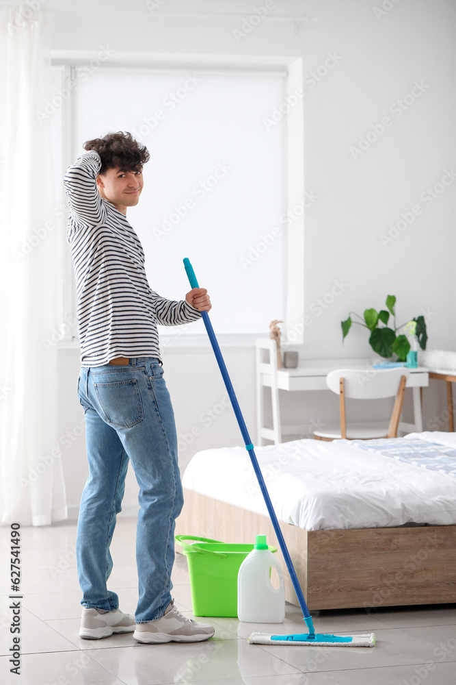 Young man mopping floor in bedroom