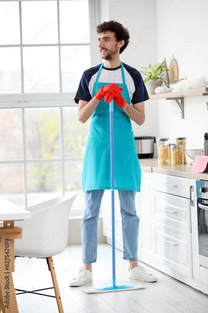 Young man mopping floor in kitchen