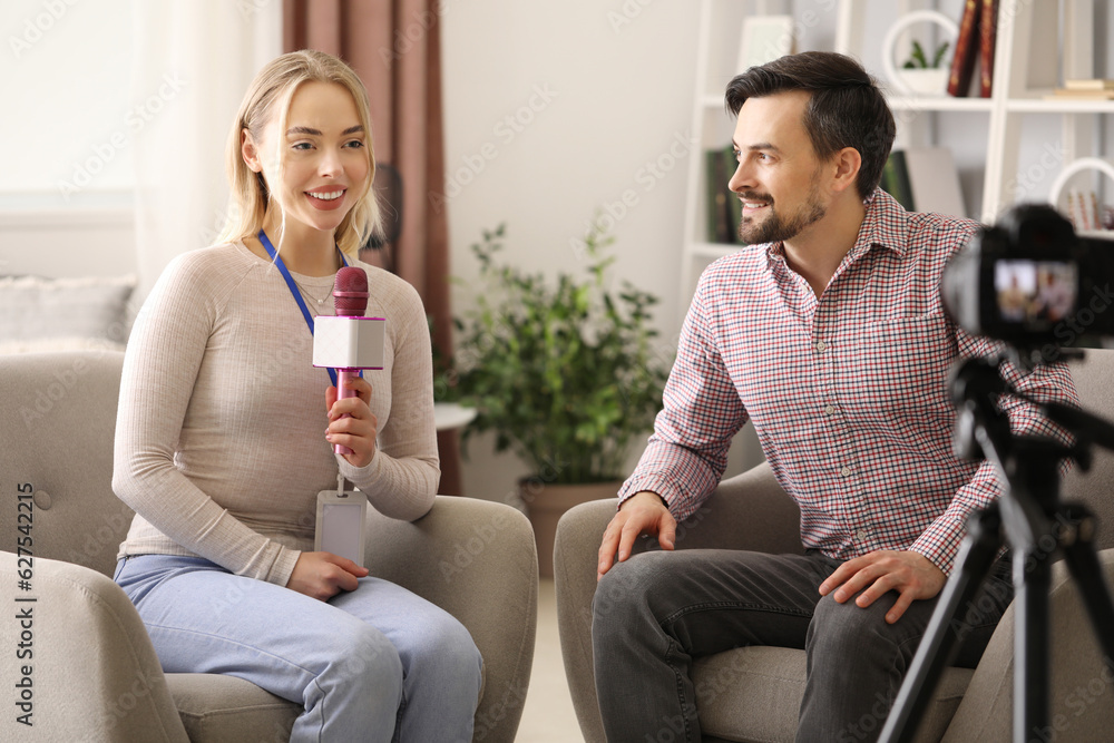 Female journalist with microphone having an interview with man in studio