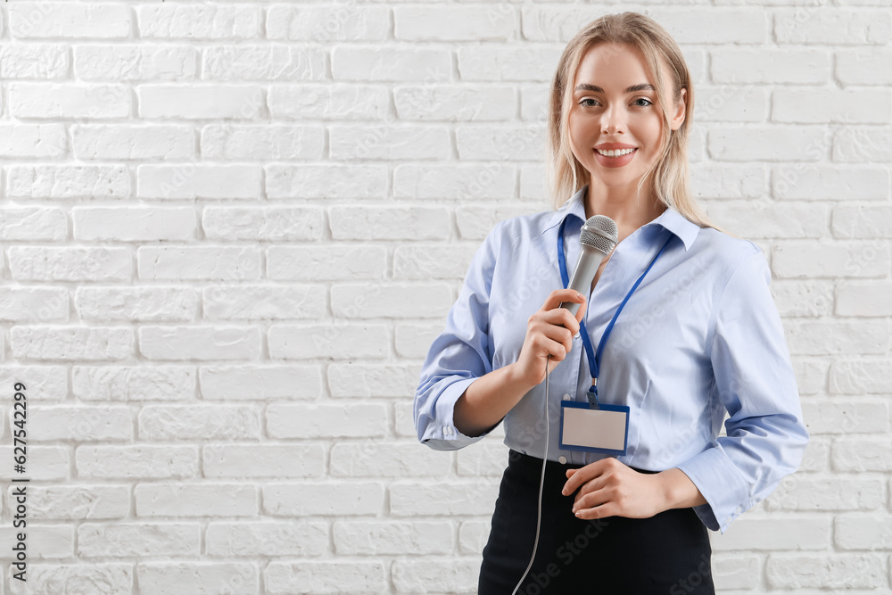 Female journalist with microphone on white brick background