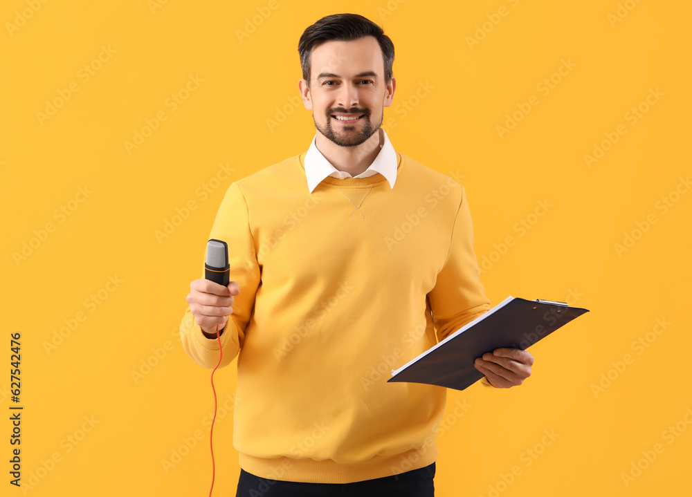 Male journalist with microphone and clipboard on yellow background