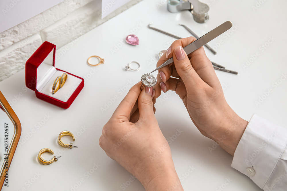 Female jeweler making ring on white table, closeup