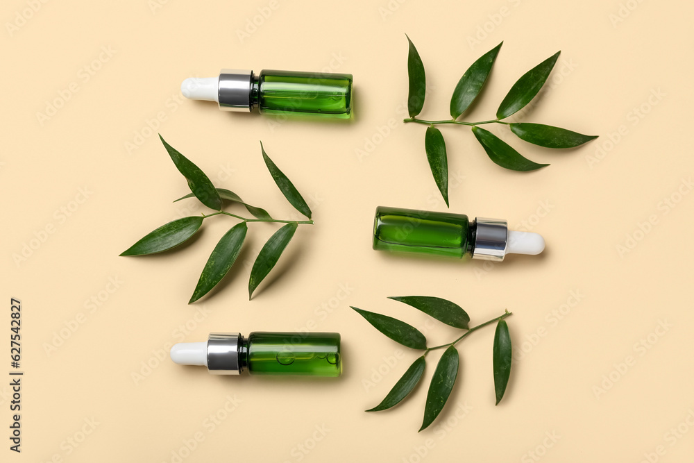 Bottles of cosmetic oil with plant twigs on beige background