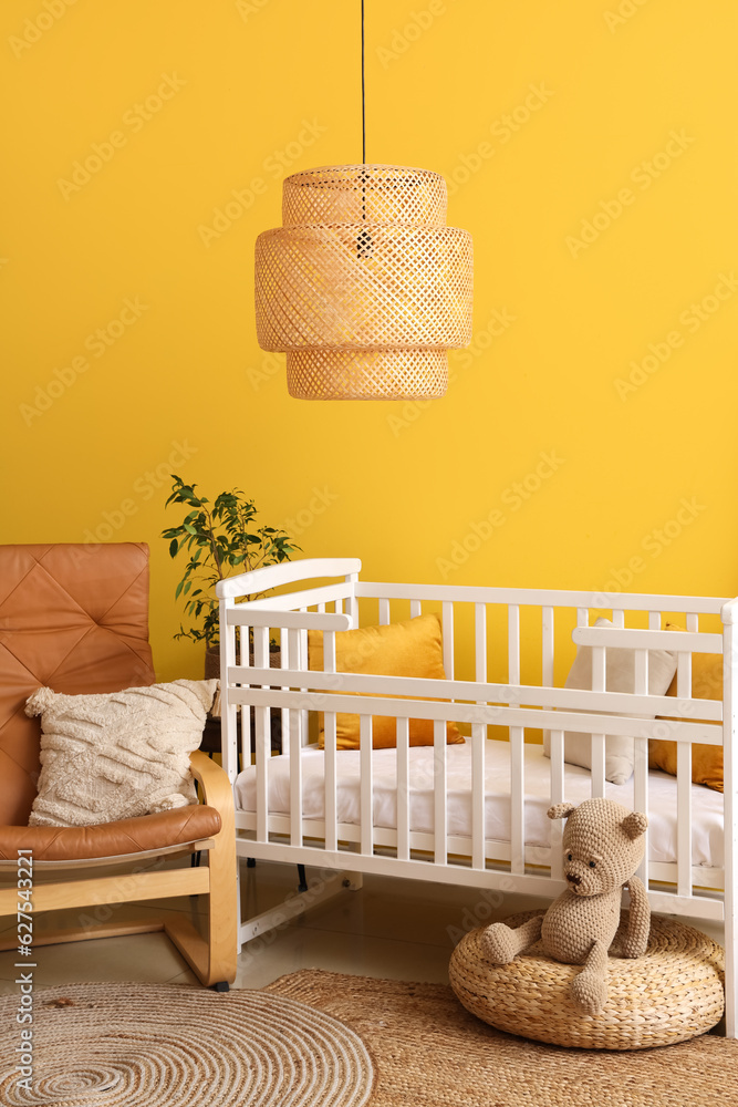 Interior of stylish bedroom with baby crib and armchair