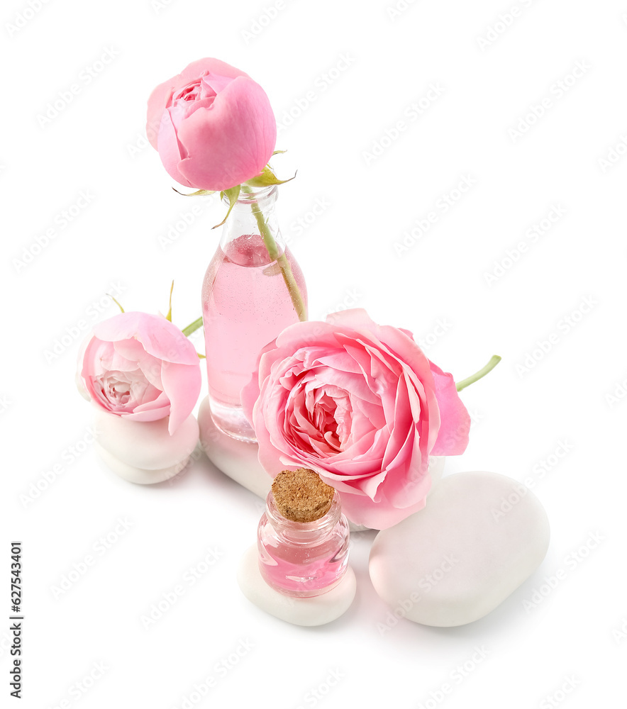 Bottles of cosmetic oil with rose extract and flowers on white background