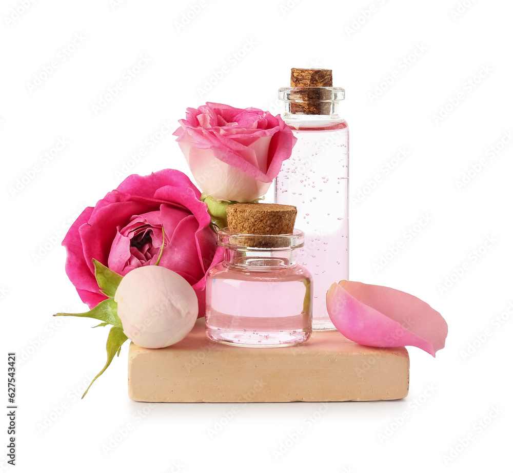 Bottles of cosmetic oil with rose extract and flowers on white background