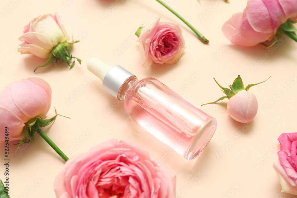 Bottle of cosmetic oil with rose extract and flowers on beige background