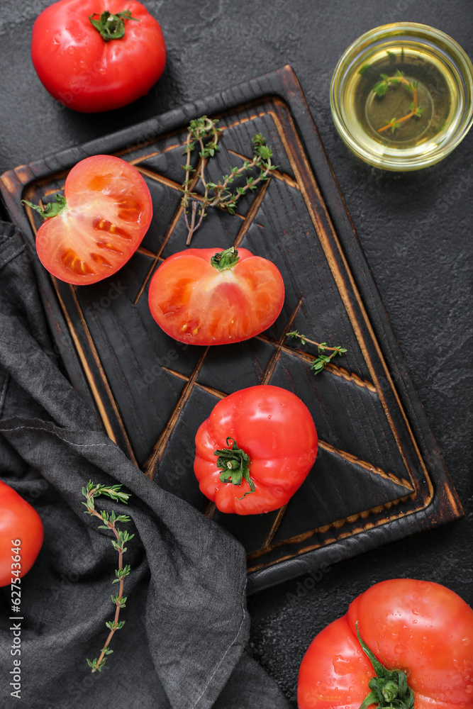 Board with fresh tomatoes on black background