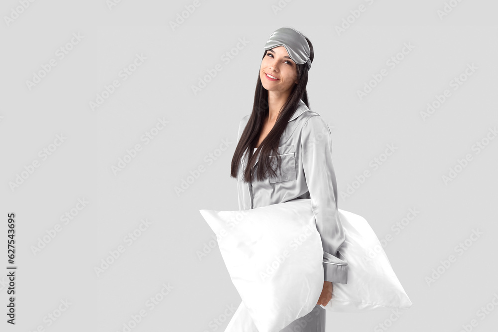 Beautiful happy young woman with soft blanket on grey background