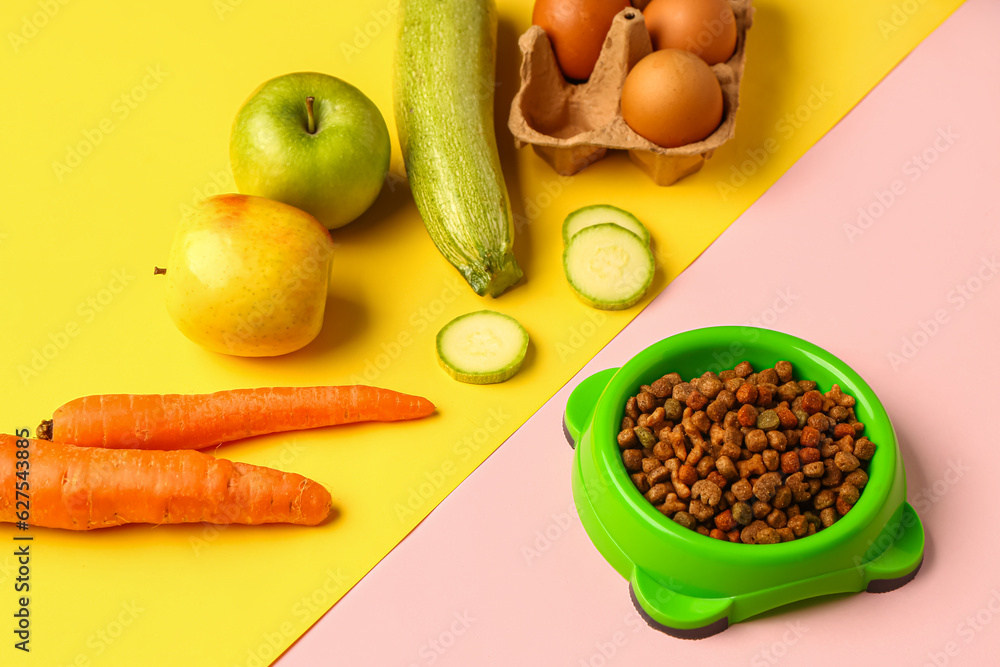 Bowl with dry pet food and natural products on color background