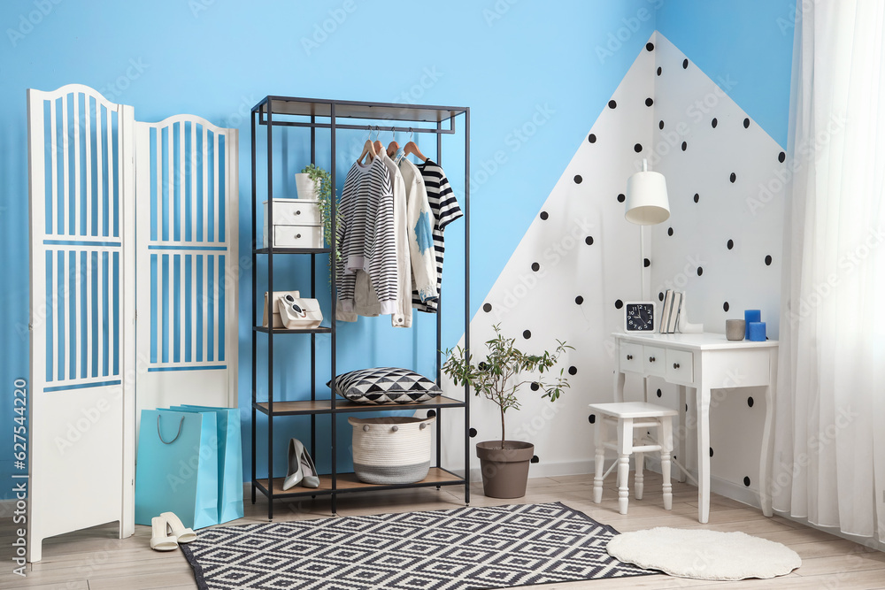 Interior of dressing room with shelving unit, clothes and table