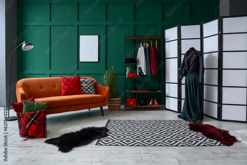 Interior of dressing room with shelving unit, clothes and sofa