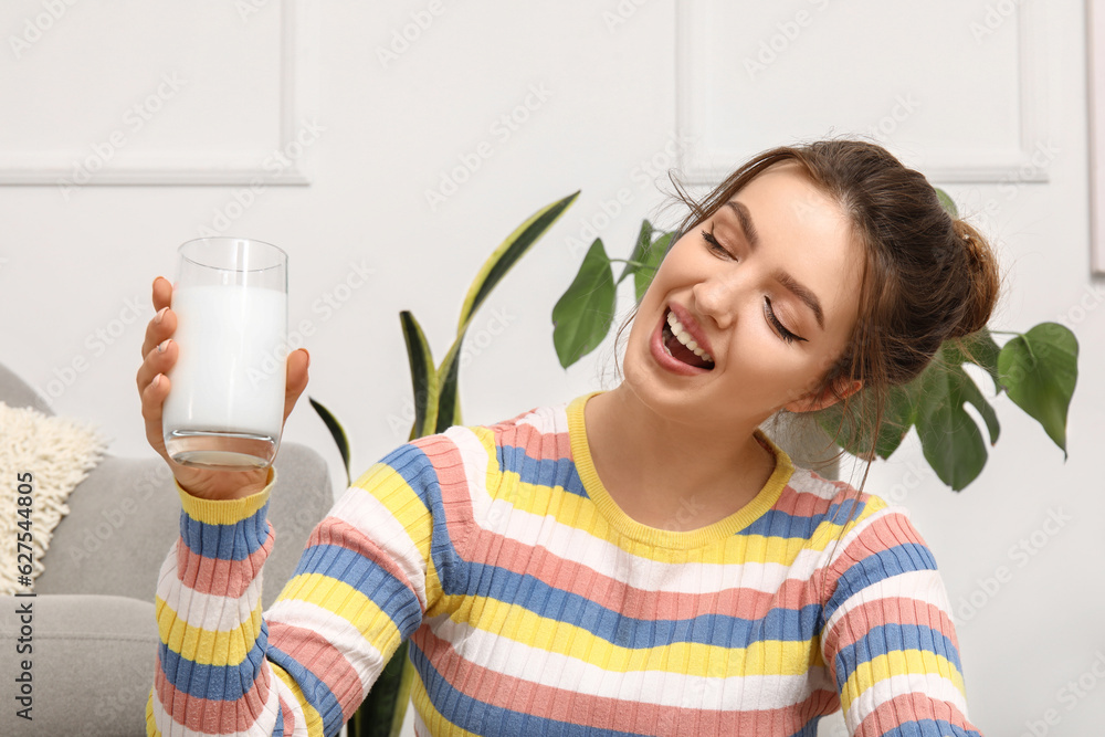 Young woman with glass of milk at home, closeup