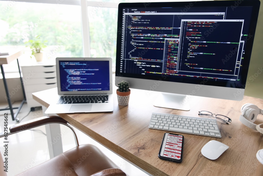 Computer monitor with programming code at programmers workplace in office