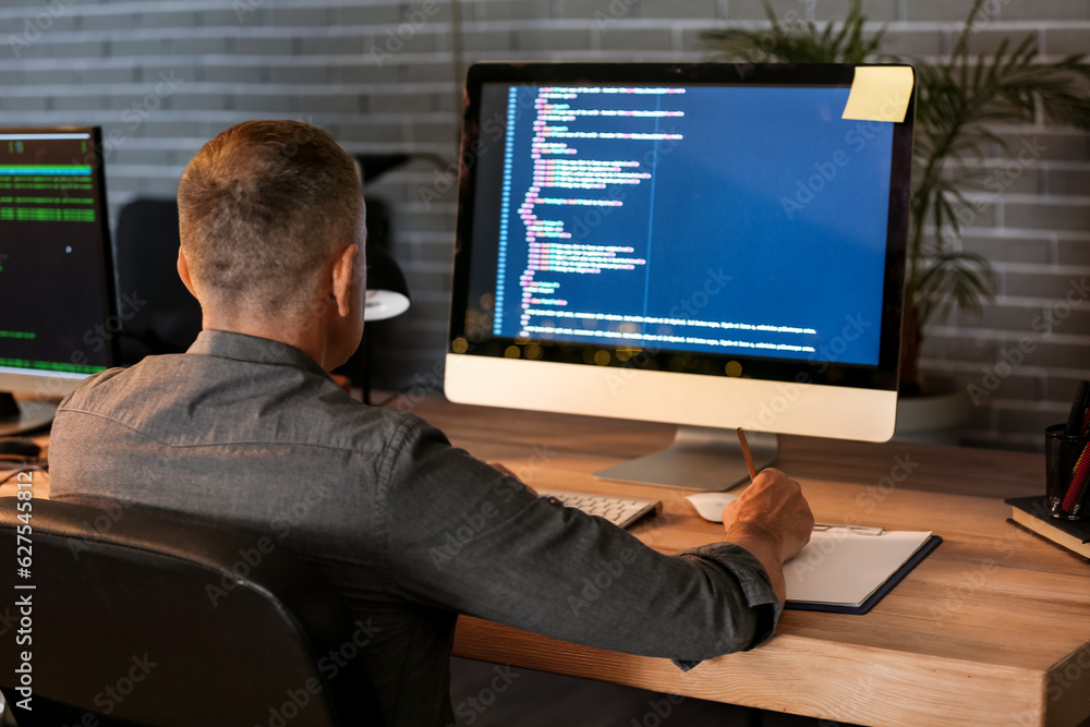 Mature male programmer working in office at night