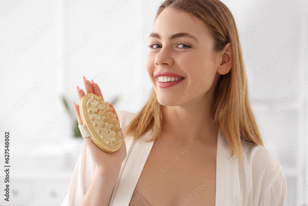 Young woman with anti-cellulite brush in bathroom, closeup