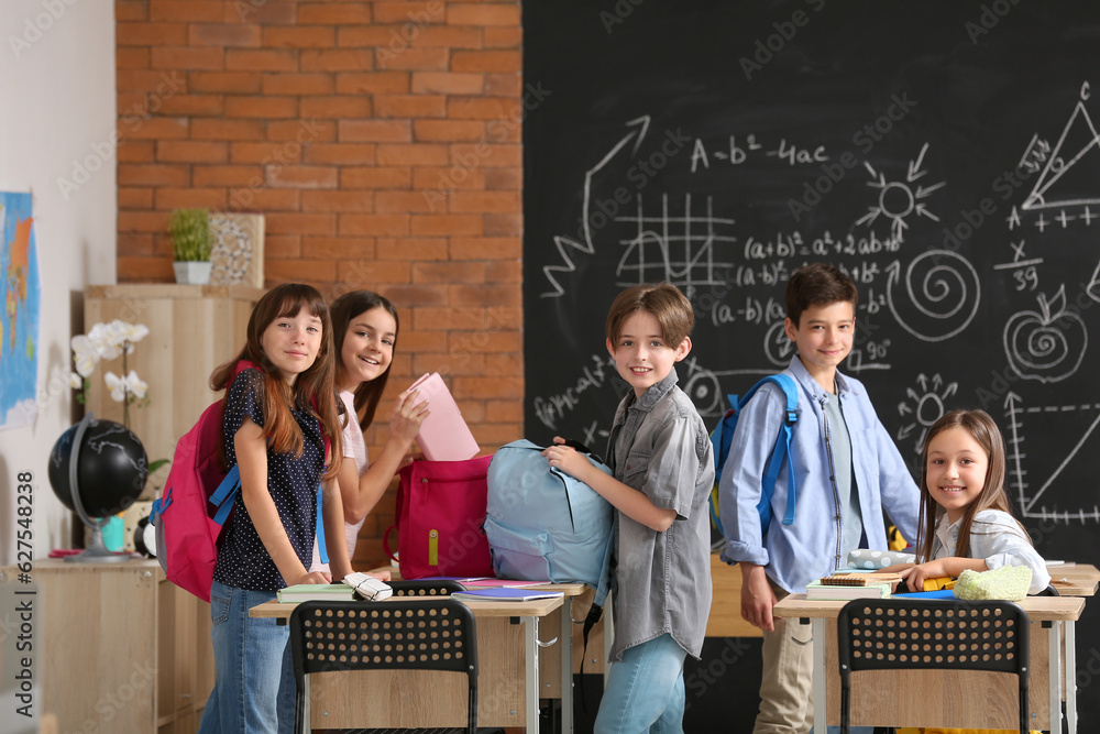 Little pupils with backpacks in classroom