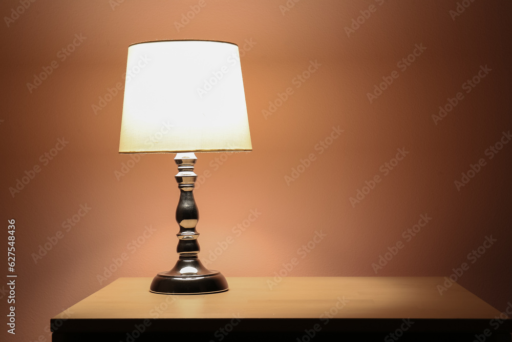 Glowing lamp on wooden table in dark room