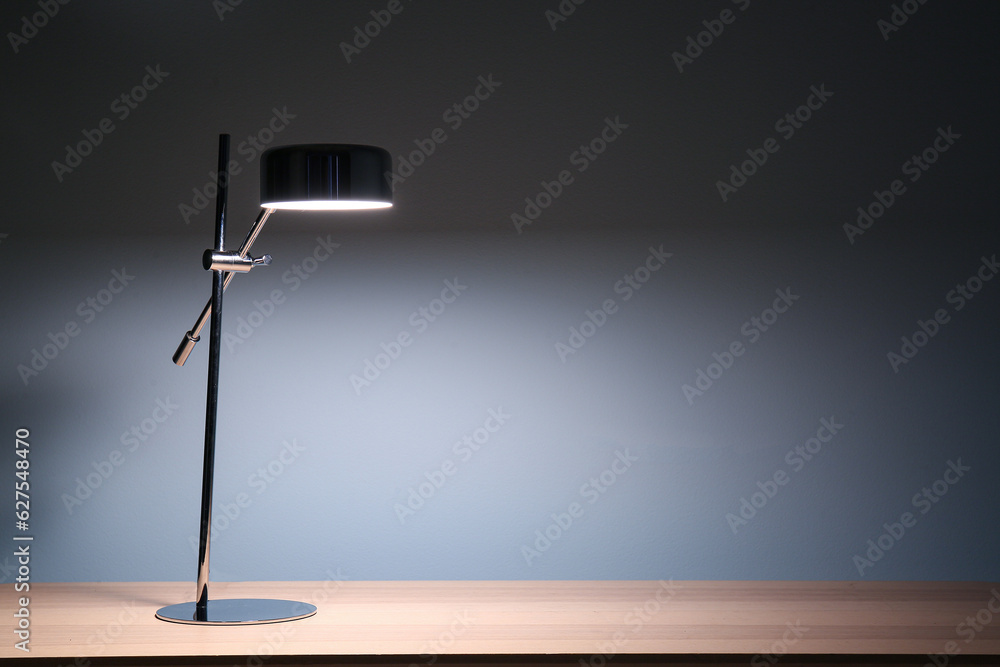 Glowing lamp on wooden table in dark room