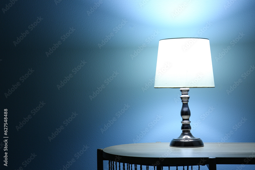 Glowing lamp on wooden table in dark room