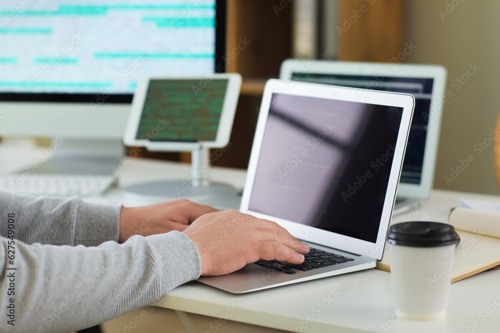 Male programmer working with laptop at table in office, closeup