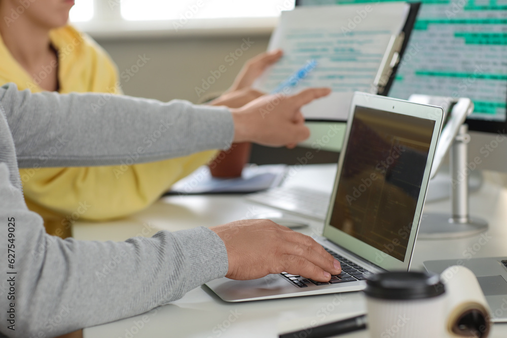 Male programmer working with laptop at table in office, closeup