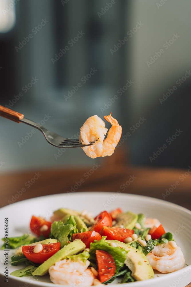 Vegetable salad with nuts on a white plate with a cup of coffee.