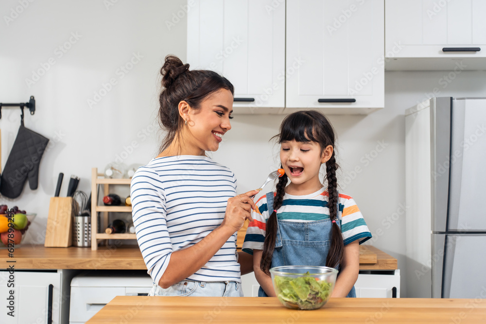 Asian mother teach and motivate young girl child eat green vegetable. 