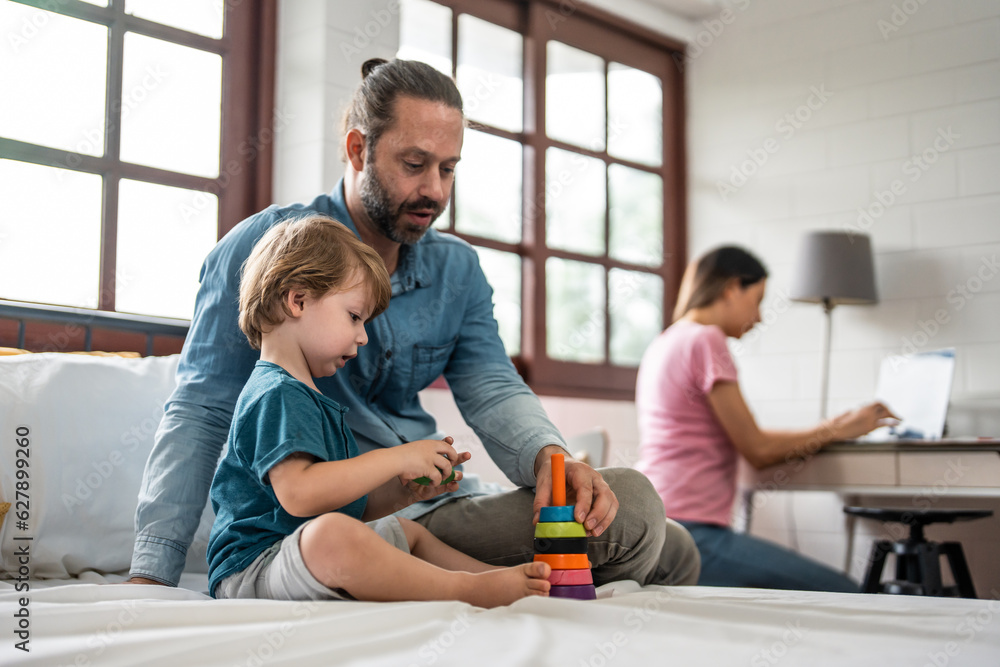 Caucasian father spend leisure time with baby boy in bedroom at house.  